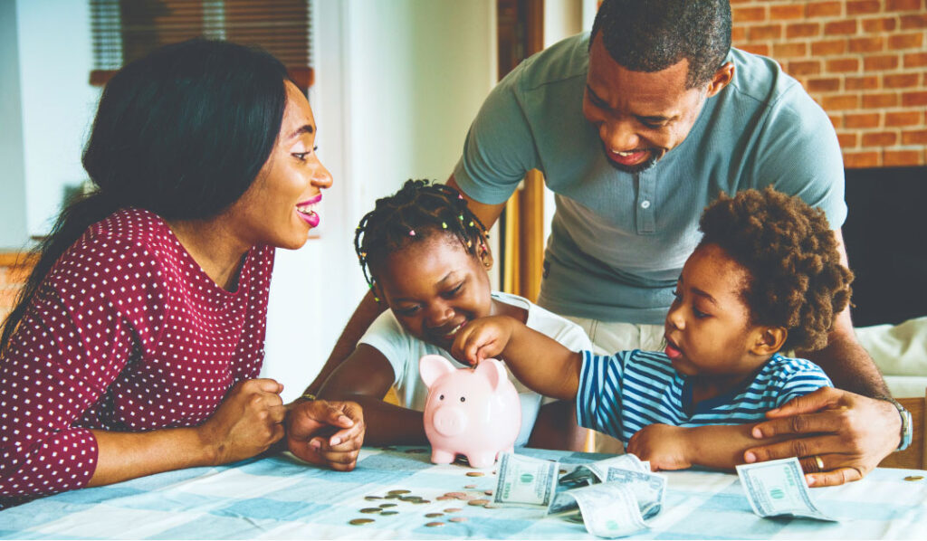 Family at table learning about saving together by placing coins in piggy bank