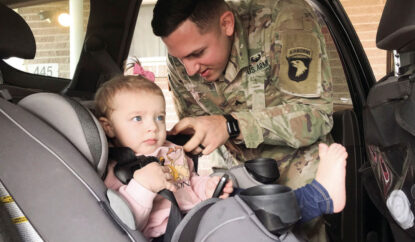 Father buckling his child into a carseat to ensure they are safe