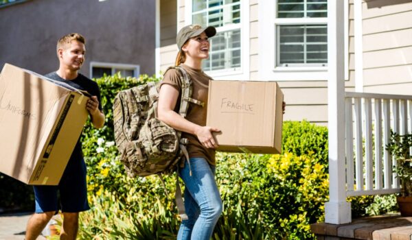 Service member and spouse carrying moving boxes