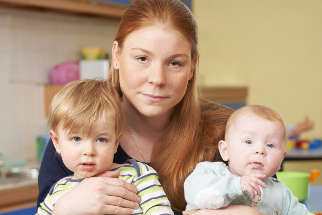 Stressed Mother With Two Young Children At Baby Group