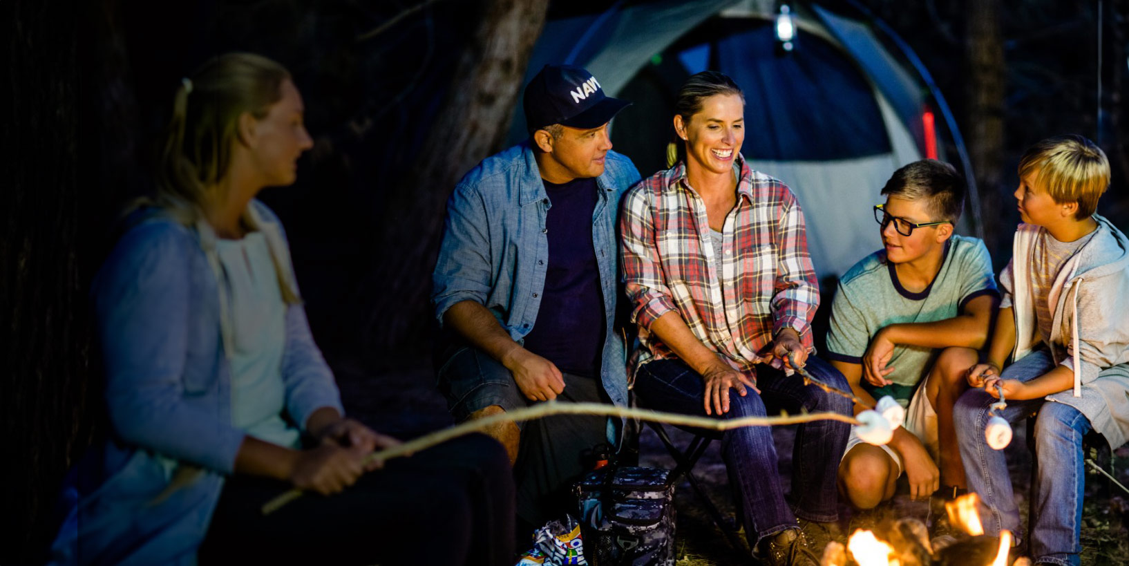 Family sitting around campfire roasting marshmallows