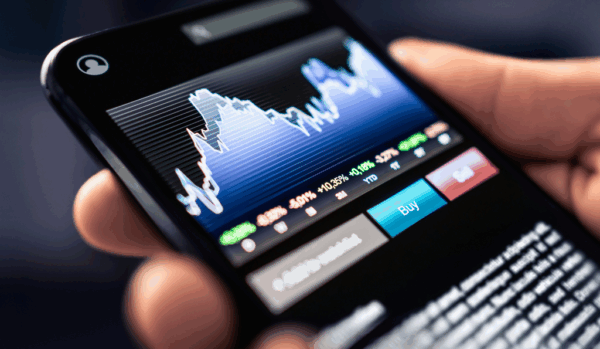 Image of hand holding cell phone with image of stock market returns.