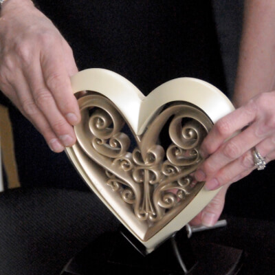 Two hands with wedding bands holding a heart