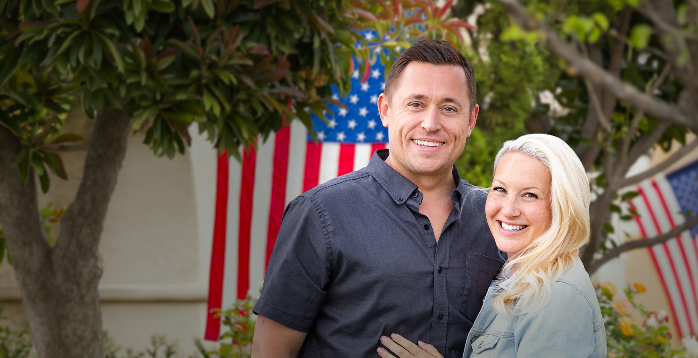A happy couple standing in front of a United Stages Flag